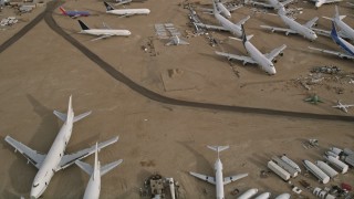 AX0006_079E - 5K stock footage aerial video fly over several jet airplanes at an aircraft boneyard in the Mojave Desert, California