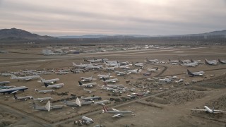 AX0006_082E - 5K aerial stock footage circle over planes at an aircraft boneyard in the Mojave Desert, California