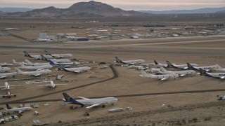 AX0006_085 - 5K aerial stock footage orbit several aircraft at a boneyard by a small airport in the desert, Mojave Air and Space Port, California