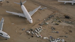 AX0006_089 - 5K aerial stock footage tilt to bird's eye of jet airplane and components at a desert boneyard, Mojave Air and Space Port, California
