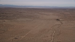 AX0006_121 - 5K stock footage aerial video pan across open desert to reveal a dry lake in Mojave Desert, California