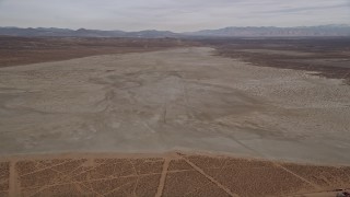AX0006_131E - 5K aerial stock footage descend toward a dry lake in the Mojave Desert, California
