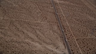 AX0006_153 - 5K stock footage aerial video tilt to bird's eye view of big rigs and cars on Highway 395 through Mojave Desert, California