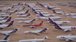 AX0007_007E - 5K aerial stock footage orbit rows of FedEx cargo planes at a desert boneyard at Victorville Airport, California at Sunset