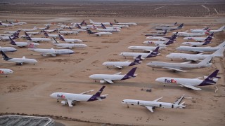 AX0007_009 - 5K aerial stock footage orbit several rows of cargo planes in an aircraft boneyard at Sunset, Victorville Airport, California