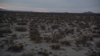 AX0007_026E - 5K aerial stock footage of flying low altitude over desert plants at twilight, Mojave Desert, California