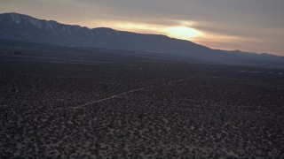 AX0007_032 - 5K aerial stock footage orbit power lines and desert road at twilight in the Mojave Desert, California