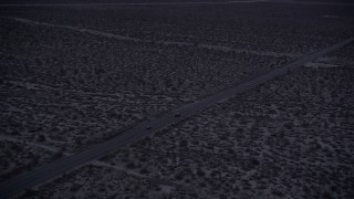 AX0007_036 - 5K aerial stock footage orbit two cars on desert highway in Mojave Desert at twilight, California