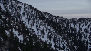 AX0008_012 - 5K aerial stock footage orbit snowy slopes of a peak in the San Gabriel Mountains at twilight in wintertime, California