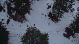 AX0008_025E - 5K aerial stock footage pan across trees and snowy slopes at Mount Baldy Ski Lifts at twilight, California