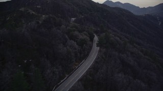 AX0008_041E - 5K aerial stock footage follow winding mountain road in the San Gabriel Mountains at twilight, California