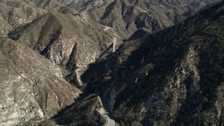 AX0009_022 - 5K aerial stock footage fly over a mountain to reveal road and small bridge in the San Gabriel Mountains, California