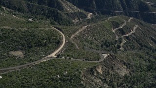 AX0009_040 - 5K aerial stock footage approach and tilt to curved roads in the San Gabriel Mountains, California