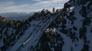 AX0009_070 - 5K aerial stock footage fly over trees on top of frozen ridge in the San Gabriel Mountains in wintertime, California