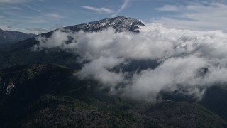AX0009_086E - 5K aerial stock footage of approaching clouds near a snowy peak in the San Bernardino Mountains, California