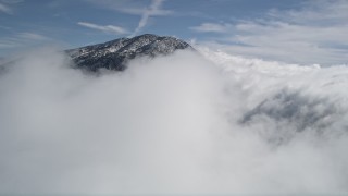 AX0009_088E - 5K aerial stock footage approaching cloud cover near a frozen peak in the San Bernardino Mountains