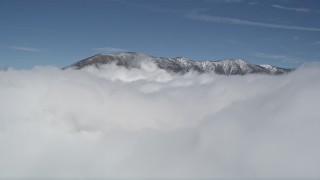AX0009_105 - 5K aerial stock footage orbit clouds to reveal snowy summits in San Bernardino Mountains in winter, California