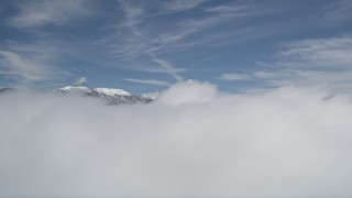 AX0009_106 - 5K aerial stock footage of snowy San Bernardino Mountains beyond thick clouds in winter, California