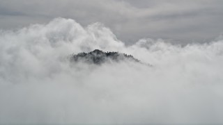 AX0009_112 - 5K aerial stock footage orbit San Bernardino Mountains peak poking through clouds, California
