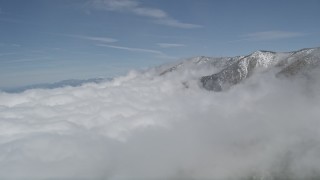 AX0009_116 - 5K aerial stock footage flyby clouds to reveal San Bernardino Mountains with winter snow, California