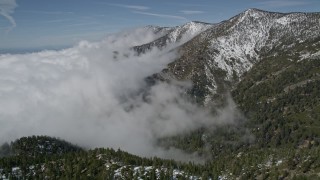 AX0009_119 - 5K aerial stock footage of clouds blanketing snowy mountain slopes in the San Bernardino Mountains, California