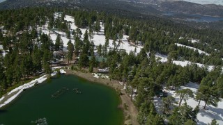 AX0009_134E - 5K aerial stock footage orbit evergreens and ski runs on a snowy slope at Snow Summit in winter, California