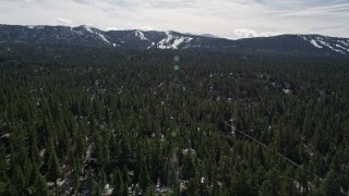 AX0010_003 - 5K stock footage aerial video of Snow Summit seen from homes and trees at Big Bear Lake in winter, California