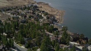 AX0010_013 - 5K aerial stock footage of orbiting lakefront homes with light snow patches at Big Bear Lake, California