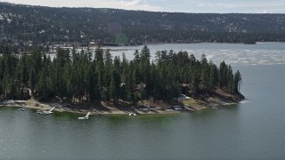 AX0010_014E - 5K aerial stock footage of approaching lakeside homes at Big Bear Lake with patches of light winter snow, California