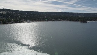 AX0010_017 - 5K aerial stock footage fly over ice patch and tilt to reveal shore of Big Bear Lake, California
