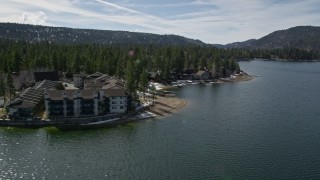 AX0010_019 - 5K aerial stock footage orbit apartment building and homes on the shore of Big Bear Lake with winter snow, California