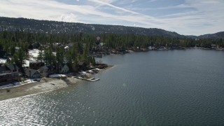 AX0010_020 - 5K aerial stock footage of lakeshore homes with light winter snow at Big Bear Lake, California