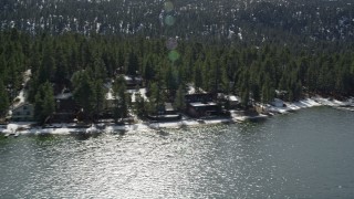 AX0010_024 - 5K aerial stock footage flyby homes on the shore of Big Bear Lake with light winter snow, California