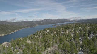 AX0010_028 - 5K aerial stock footage pan across snowy mountain and forest to reveal Big Bear Lake in winter, California