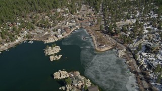 AX0010_031 - 5K aerial stock footage approach waterfront homes and the town on the shore of Big Bear Lake in winter, California