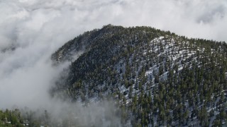AX0010_071 - 5K aerial stock footage orbit clouds surrounding mountains with snow in the San Jacinto Mountains, California