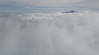 AX0010_072 - 5K aerial stock footage tilt up from clouds to reveal distant peak in San Jacinto Mountains, California