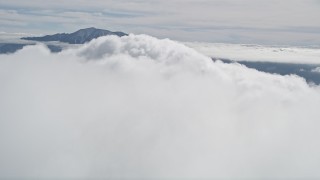 AX0010_078 - 5K aerial stock footage orbit a large white cloud near a mountain peak in the San Jacinto Mountains, California