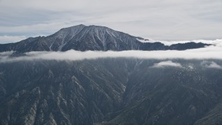 AX0010_086 - 5K aerial stock footage of tall mountain peak ringed by clouds in the San Jacinto Mountains, California