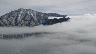 AX0010_090 - 5K aerial stock footage orbit summit of a peak with light snow in the San Jacinto Mountains, California