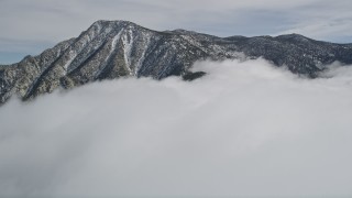 AX0010_093 - 5K aerial stock footage tilt from snowy mountain to reveal tall peak in the San Jacinto Mountains in winter, California