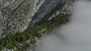 AX0010_096 - 5K aerial stock footage approach a ridge with snow and clouds in the San Jacinto Mountains in wintertime, California