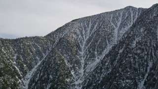 AX0010_101 - 5K aerial stock footage orbit a mountain peak with light winter snow in the San Jacinto Mountains, California