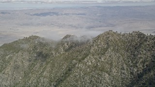 AX0010_103 - 5K aerial stock footage of rugged mountain ridge in the San Jacinto Mountains with Coachella Valley in the distance, California