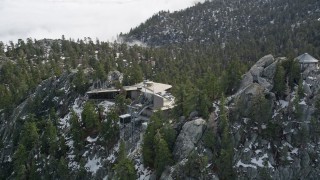 AX0010_109E - 5K aerial stock footage of circling a mountain tram station in the San Jacinto Mountains with winter snow, California