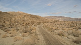 AX0011_008E - 5K aerial stock footage of following desert road through Joshua Tree National Park, California