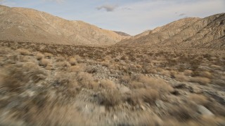AX0011_016 - 5K aerial stock footage of low altitude fly over of desert plants toward mountains in Joshua Tree National Park, California