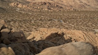 AX0011_041 - 5K aerial stock footage flyby rock formation revealing desert road, Joshua Tree National Park, California