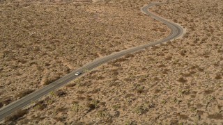 AX0011_043E - 5K aerial stock footage of tracking a car on a desert road, Joshua Tree National Park, California