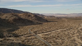 AX0011_045 - 5K stock footage aerial video of flying by a winding desert road, Joshua Tree National Park, California